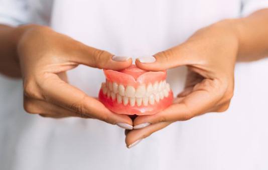Lady presents viewer with dentures
