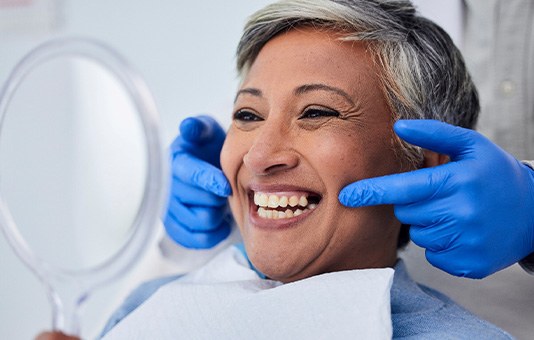 Woman smiling at reflection in handheld mirror