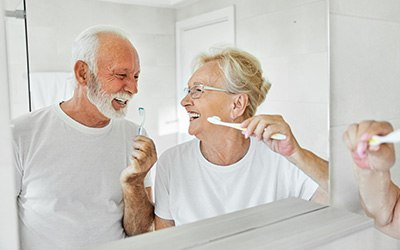 Senior couple smiling while brushing their teeth