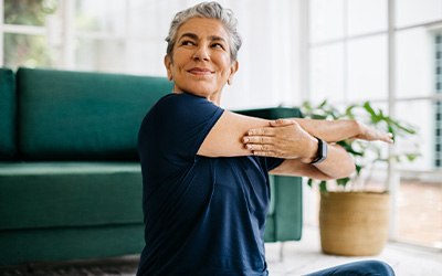 Senior woman smiling while stretching at home