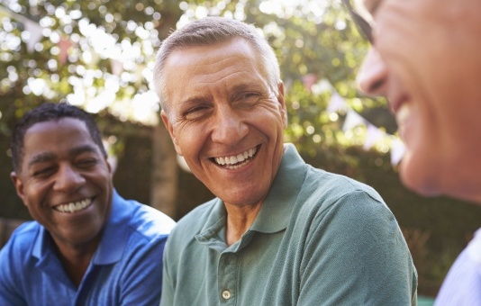 Group of friends smiling together after dental implant supported tooth replacement