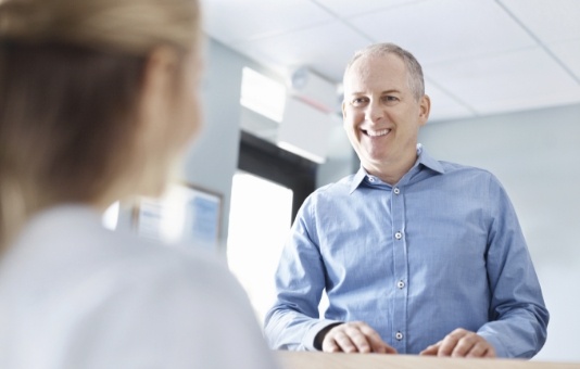 Man smiling at dental team member at reception desk