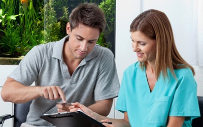 A man paying the cost of dental implants in Garland