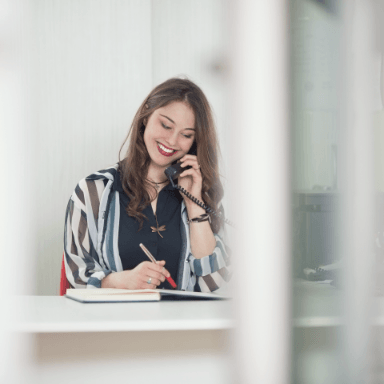 Smiling woman sitting at desk while talking on phone