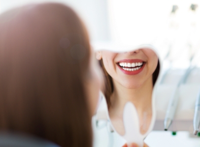 Woman looking at smile in tooth shaped mirror