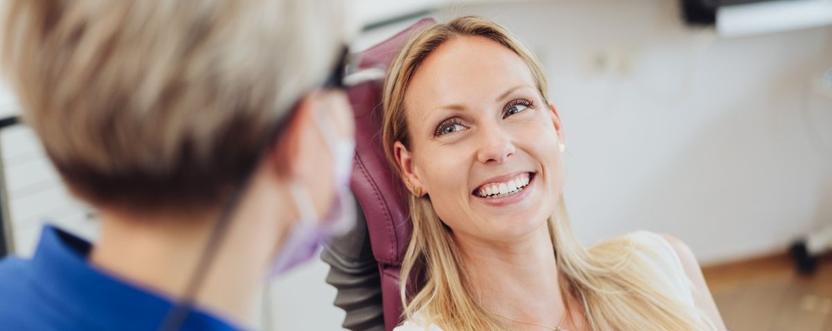 Woman in dental chair smiling at dentist