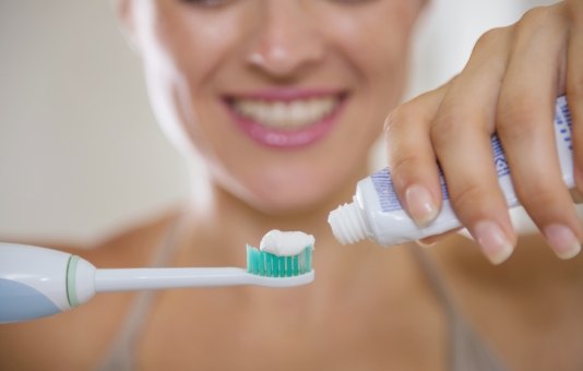 Woman putting toothpaste on toothbrush