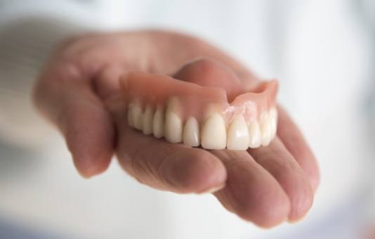 Hand holding a full denture