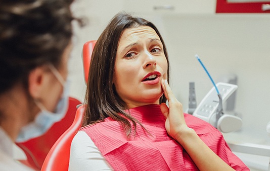 Patient talking to their dentist and holding their cheek