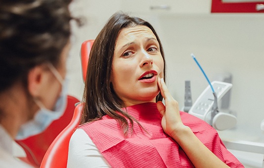 Patient talking to their dentist and holding their cheek