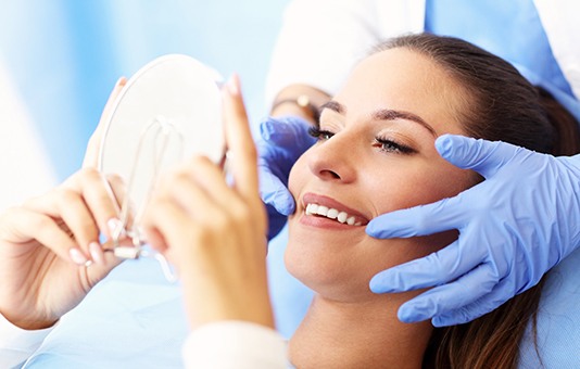 Woman looking in the mirror at the dentist’s office