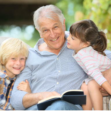 Older man with grandchildren smiling after emergency dentistry