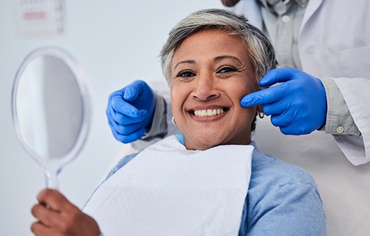 Woman smiling while holding handheld mirror