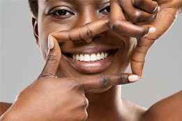 Smiling woman using her hands to frame her white teeth